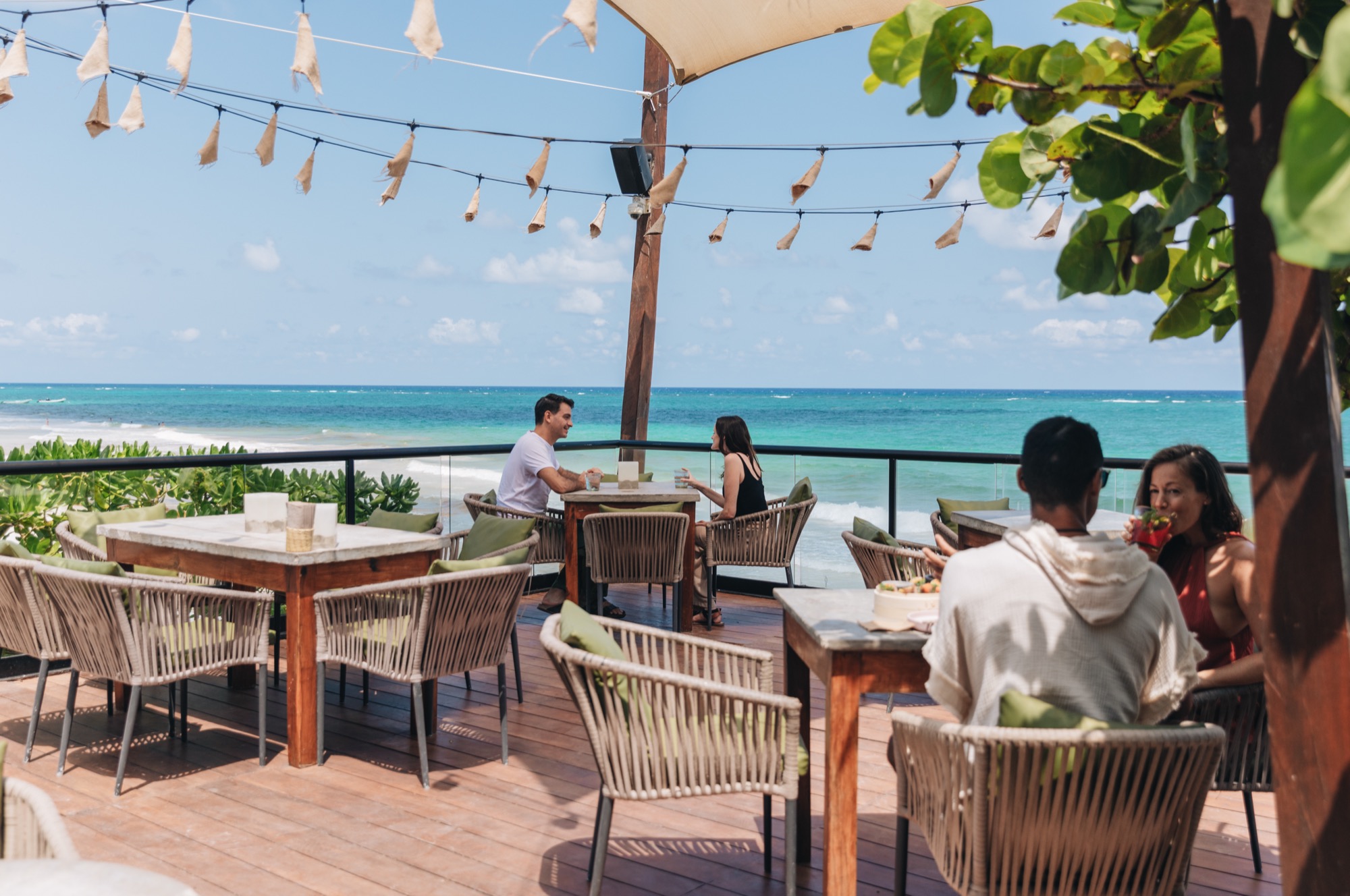Guests dining on Mezzanine’s open-air terrace overlooking the Caribbean and the beach.